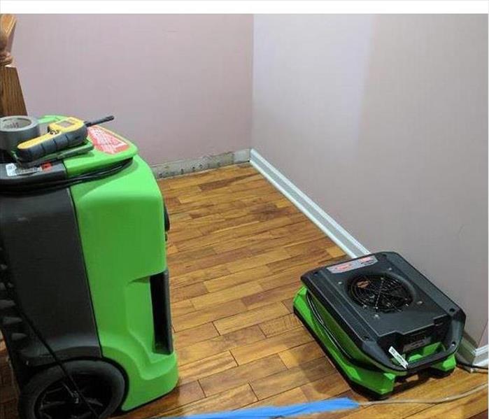 SERVPRO equipment with hardwood flooring and wall without a baseboard