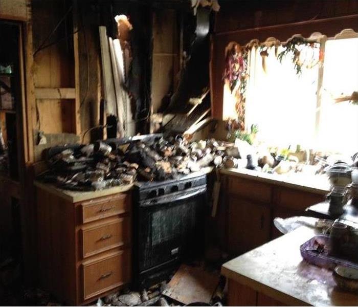 Kitchen with heavy fire damage and debris on the stovetop