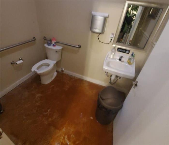 Water on the bathroom floor with a sink and toilet
