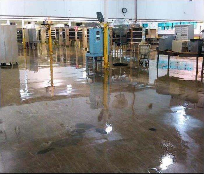 concrete floor with water reflecting from a flood with equipment spread out in a warehouse