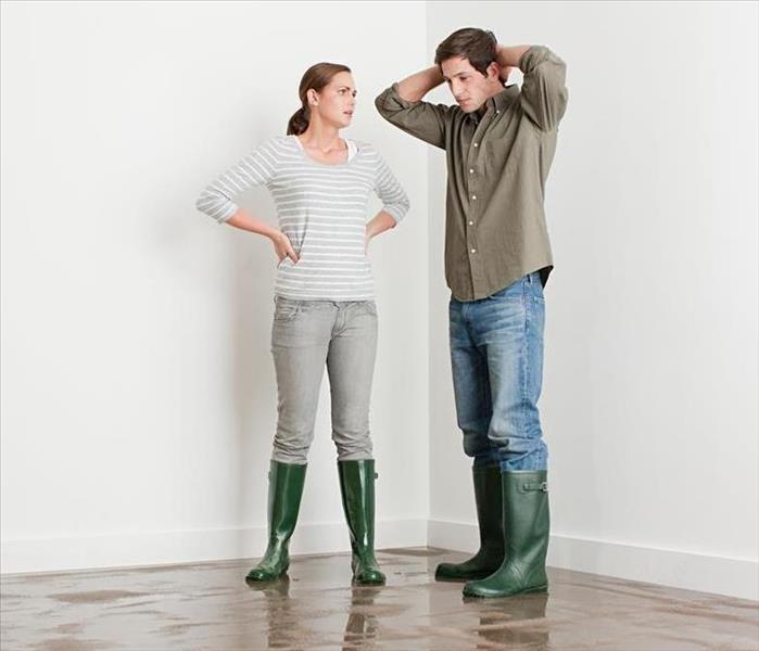 Two people standing in a room with green rain boots on. 